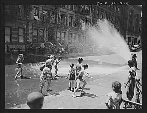 Children escape the heat of the East Side by using fire hydrant as a shower bath