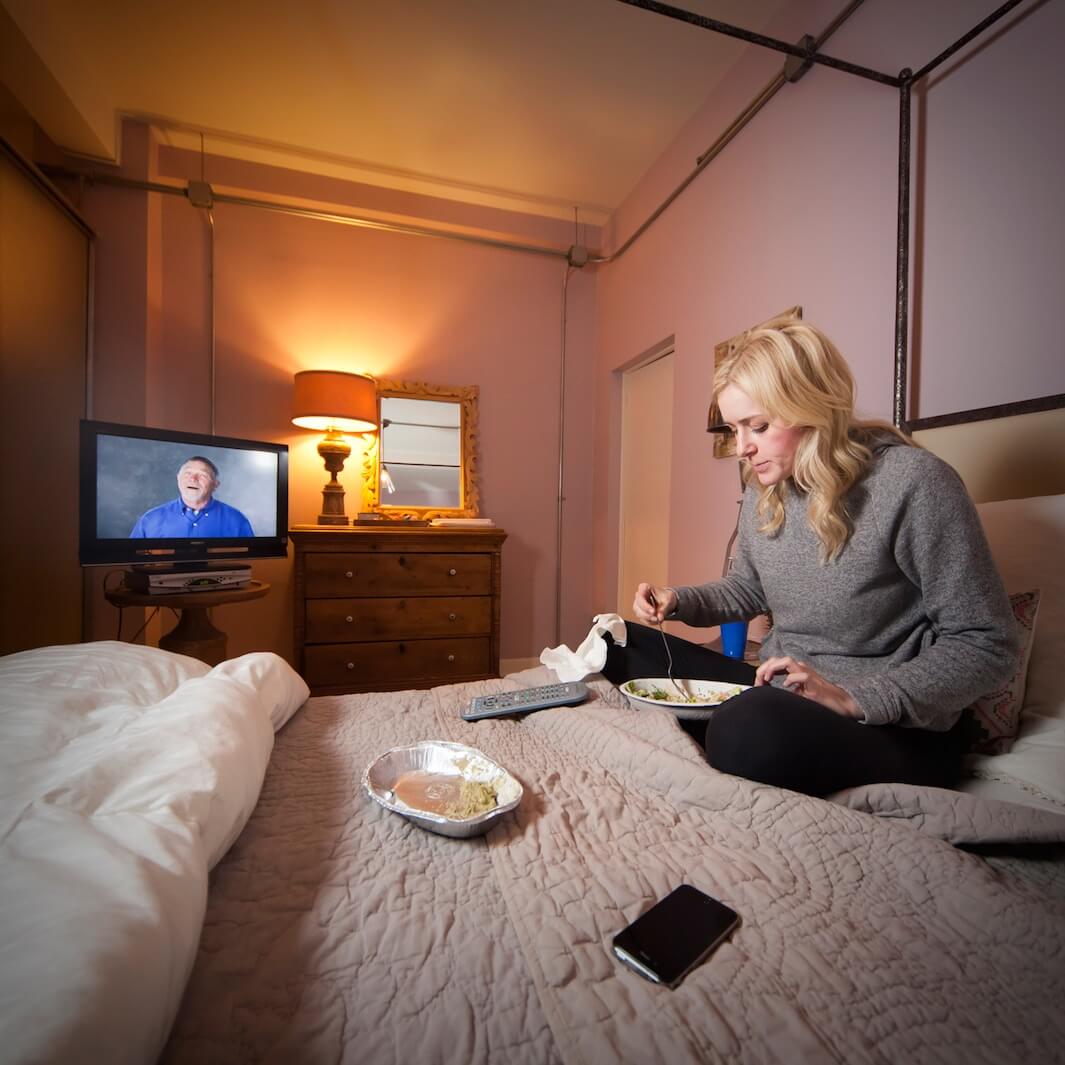 Jessie Zinke, a designer, has leftover for dinner on her bed while watching her favorite TV show. Age: 27. Time: 6:54 p.m. Location: Chelsea, New York.